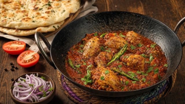 Balochi chicken karahi in a rich tomato sauce in a black iron karahi with naan