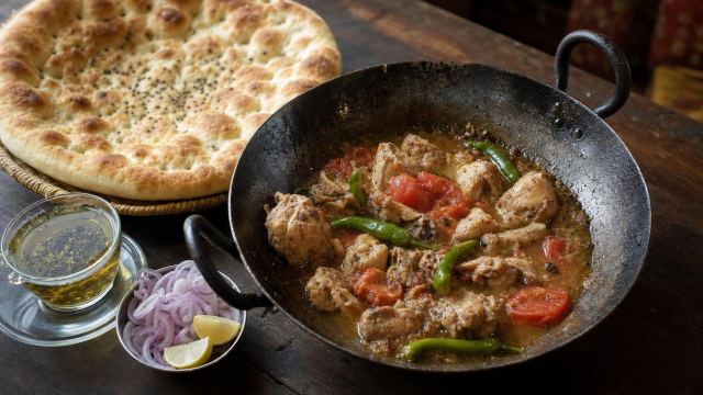 Peshawari chicken karahi with tomatoes and green chillies in a black iron karahi